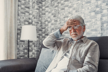 Frustrated unhealthy senior mature man touching head, having painful feelings sitting alone at...