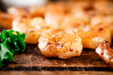 Grilled shrimp with parsley on a wooden background.