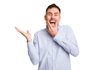 Young caucasian man cut out isolated holds copy space on a palm, keep hand over cheek. Amazed and delighted.