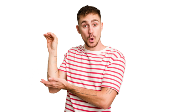 Young caucasian man cut out isolated shocked and amazed holding a copy space between hands.