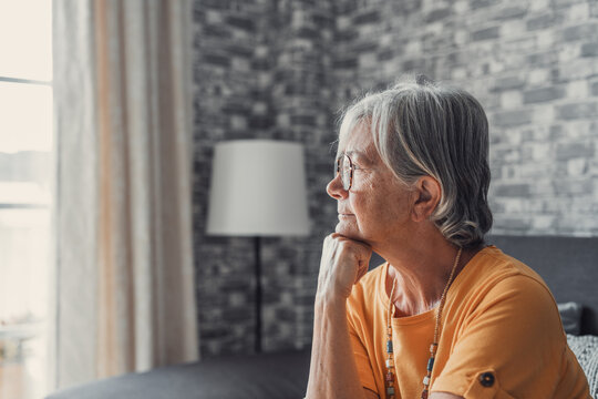 Face of senior caucasian hoary woman looking away deep in sad thoughts feels lonely close up portrait, recollect memories and life moments, depressed grandmother alone indoors, yearning for husband 