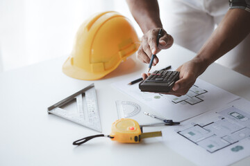 The architect is pointing to the house plans he has designed, he is meeting with engineers and...