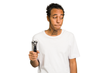 Young African American man holding a razor isolated confused, feels doubtful and unsure.