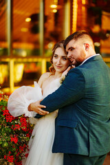 the bride and groom embrace on the terrace in the park near the restaurant.