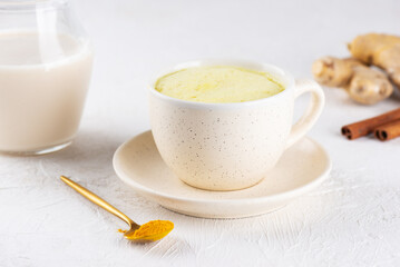 Whipped turmeric golden latte from almond milk, ginger, turmeric and cinnamon in a mug, sugar and lactose free.