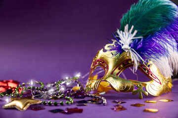 Carnival Party - A Venetian Mask with green and purple beads and sequins. Purple background with copy space. The concept of Masquerade disguise.