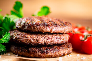 Burger grill on a cutting board with greens and tomatoes. 