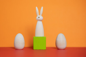 petit lapin sur un support vert et deux oeufs en bois, décoration de Pâques moderne