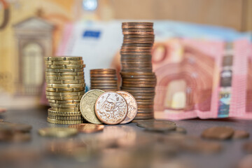 ensemble de pièces empilées avec des billets en fond, en euros