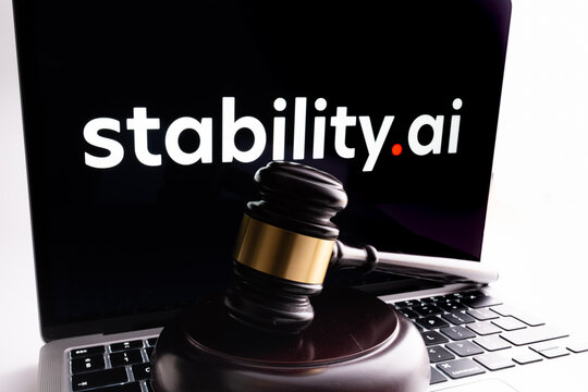 Gravel seen in front and Stability AI company logo on the blurred laptop. Concept for a lawsuit against artificial intelligence software developer. Stafford, United Kingdom, January 23, 2023