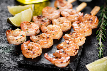 Grilled shrimp on a stone board with pieces of lime. 