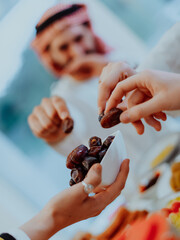 Modern multiethnic muslim family sharing a bowl of dates while enjoying iftar dinner together...