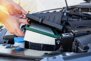 Replacing a new air filter in a passenger car, engine compartment. Car maintenance. Automotive mechanic installs a new engine air filter, close-up