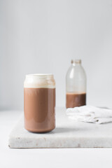Mocha latte with whipped cream in a can shaped glass,  iced mocha with foam on a table