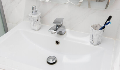 Modern and clean washbasin with pop-up waste. Washbasin interior with liquid soap and toothbrushes.