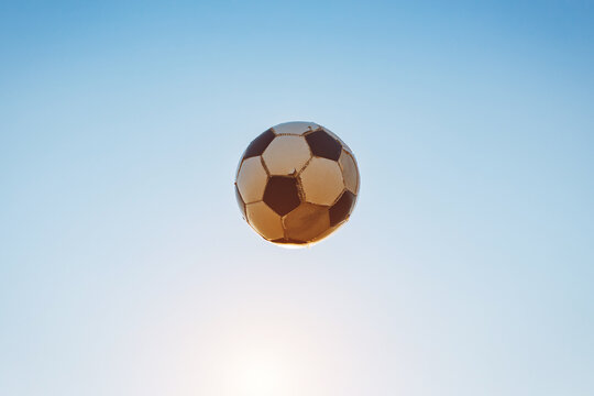 Low angle view of classic black and white ball or soccer football flying in twiligth sky. Sport game and athlete concept with no people.