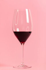 Vertical photo of glass of red wine on light pink background