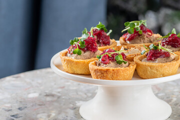 Tartlets stuffed with codfish liver, codfish caviar and microgreens. Traditional cold portioned appetizer in a pastry basket.