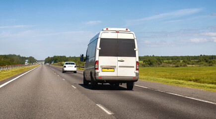 Fototapeta na wymiar Passenger minibus moves along the motorway in summer against the blue sky. Passenger transportation business concept. Intercity traffic. Copy space for text