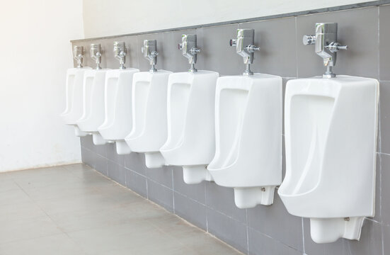 Men's room with white porcelain urinals in line. Modern clean public toilets with tiles. Comfort male toilet urinal concept.