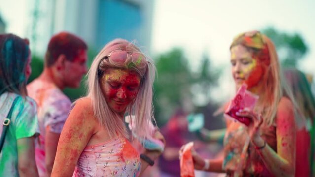 Two girls in holi colors dance and have fun at the festival