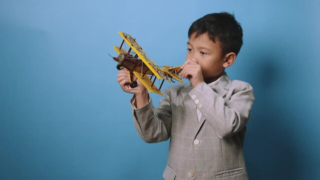 the studio shot isolated image of the boy playing the miniture airplane with the blue backdrop