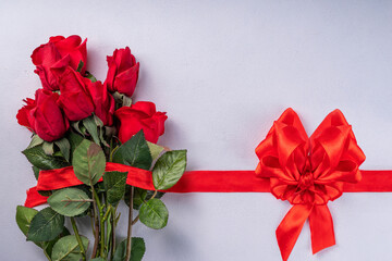 Valentine's Day, International Women's Day, Mother's Day greeting card background. Red rose flowers bouquet, with festive ribbon, tied bow in shape of heart, top view copy space