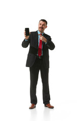 Businessman in a suit pointing at phone screen over white studio background. Online work, cooperation, assistance. Concept of business, career, innovations, ad