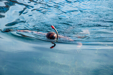 The diver swims in a wetsuit, flippers and a mask with a tube. The rescuer divers carries out work...