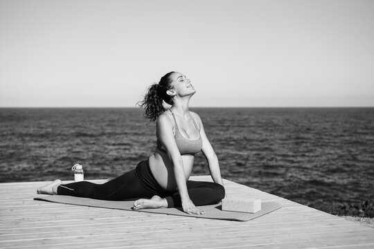 Young pregnant woman doing yoga outdoor - Maternity concept - Focus on face - Black and white editing