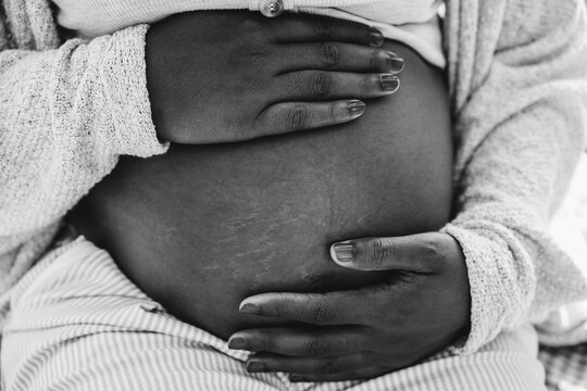 Close up of african pregnant woman holding her belly - Focus on hands - Black and white editing