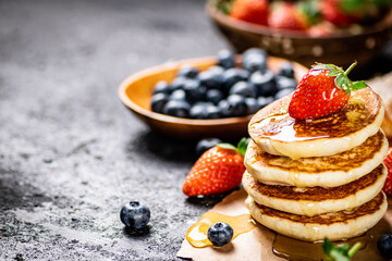 A pile of pancakes with berries and honey. 