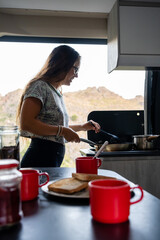 Young woman making breakfast in a motor home.