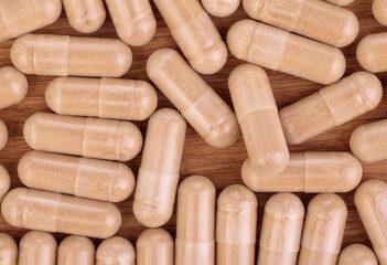 Herbal powder capsules on wooden background. Top view. Flat lay. Close-up