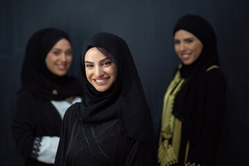 Group portrait of beautiful Muslim women in a fashionable dress with hijab isolated on black...