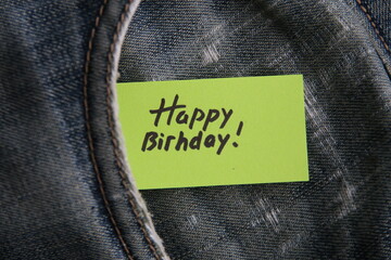 Happy birthday inscription on a paper tag in a jeans pocket.