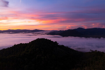 Aerial view of flowing fog waves on mountain tropical rainforest,Bird eye view image over the clouds Amazing nature background with clouds and mountain peaks in Thailand