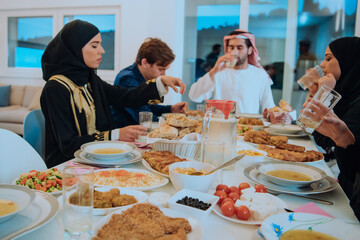  Muslim family having Iftar dinner drinking water to break feast. Eating traditional food during Ramadan feasting month at home. The Islamic Halal Eating and Drinking in modern home 