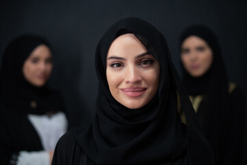 Group portrait of beautiful Muslim women in a fashionable dress with hijab isolated on black background