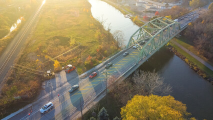 Top view traffic on historic Pratt through truss bridge over Erie Canal colorful fall foliage in late afternoon light, Pittsford, New York