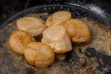 Scallops sauteed in butter, cooking in frying pan