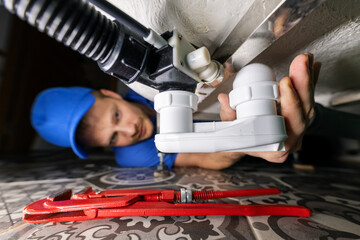 plumbing service. plumber at work in bathroom. repair and install siphon under the bath