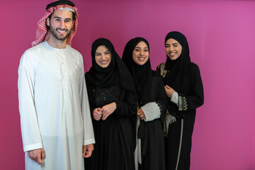 Group portrait of young Muslim people Arabian men with three Muslim women in a fashionable dress with hijab isolated on a pink background