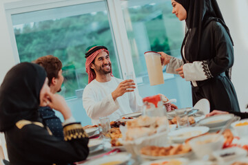  Muslim family having Iftar dinner drinking water to break feast. Eating traditional food during Ramadan feasting month at home. The Islamic Halal Eating and Drinking in modern home 