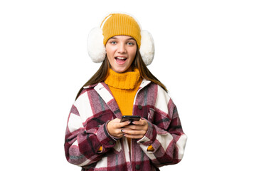 Teenager caucasian girl wearing winter muffs over isolated background surprised and sending a message
