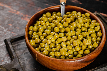Canned green peas in a wooden bowl. 
