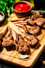 Grilled rack of lamb on a cutting board with parsley and tomato sauce. 