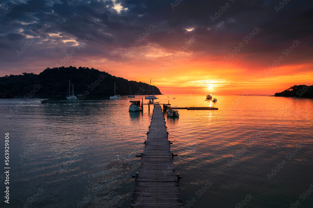 Wall mural beautiful sunset over tropical sea and wooden pier, sightseeing boat and tourist enjoying in koh koo