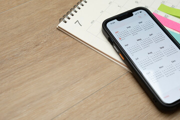 close up of calendar and smart phone application on the wooden table background, planning for business meeting or travel planning concept