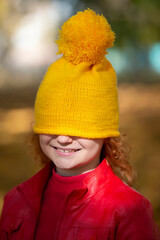 The little girl pulled a yellow knitted hat over her eyes. Fall has come.